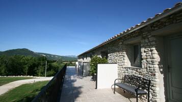 Un bâtiment en pierre doté d’un balcon, d’un banc et offrant une vue sur les montagnes.