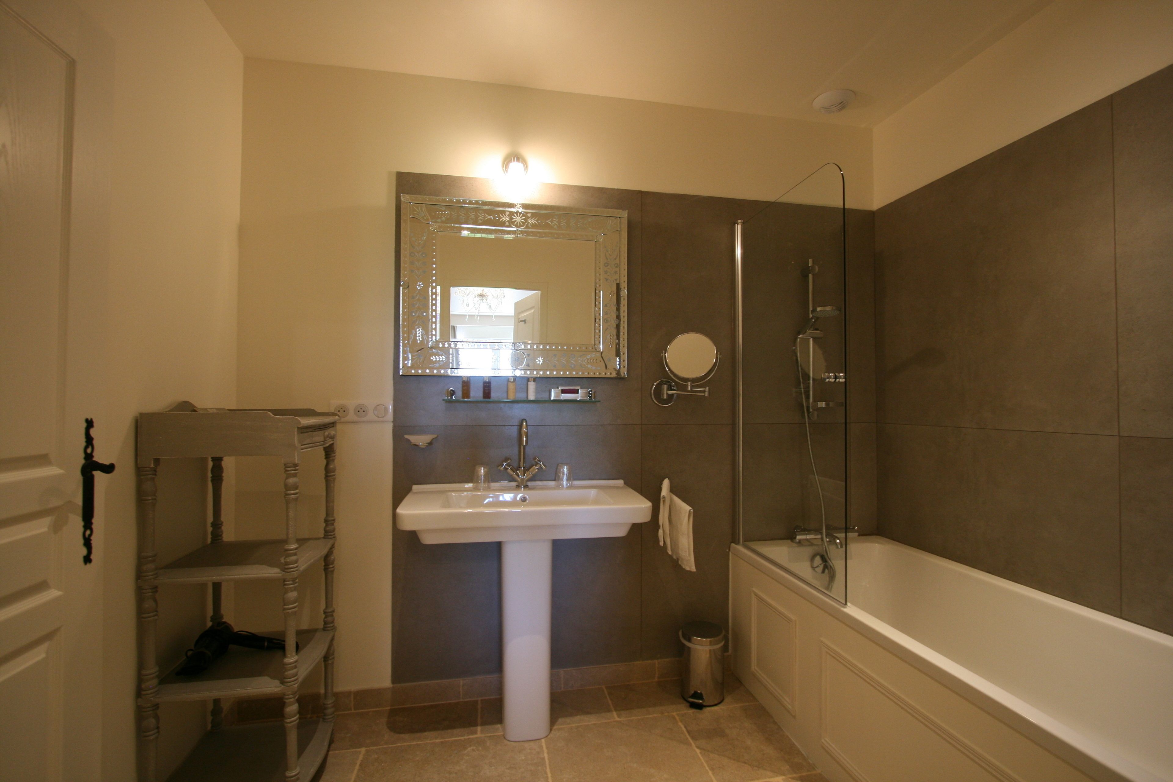 A bathroom with a pedestal sink, a large mirror, a shower, and a bathtub.