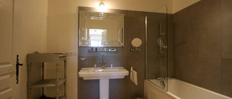 A bathroom with a pedestal sink, a large mirror, a shower, and a bathtub.
