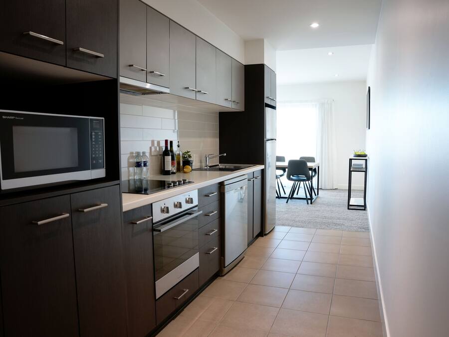 Una cocina moderna con armarios oscuros, un microondas y un comedor con mesa y sillas.