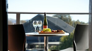 A table with a bottle of wine, two glasses, and a plate of grapes and nuts.