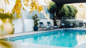A swimming pool with lounge chairs and potted plants.