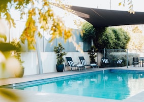 Una piscina al aire libre, sillones reclinables de piscina