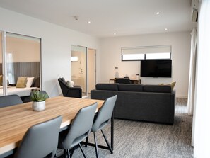 Relax in a spacious room with a large flat-screen TV, comfortable sofa, and dining area.