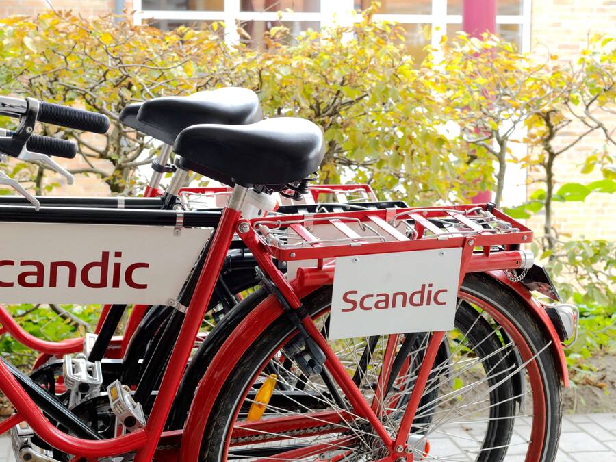 Una bicicleta roja con una cesta y un letrero que dice "Scandic".