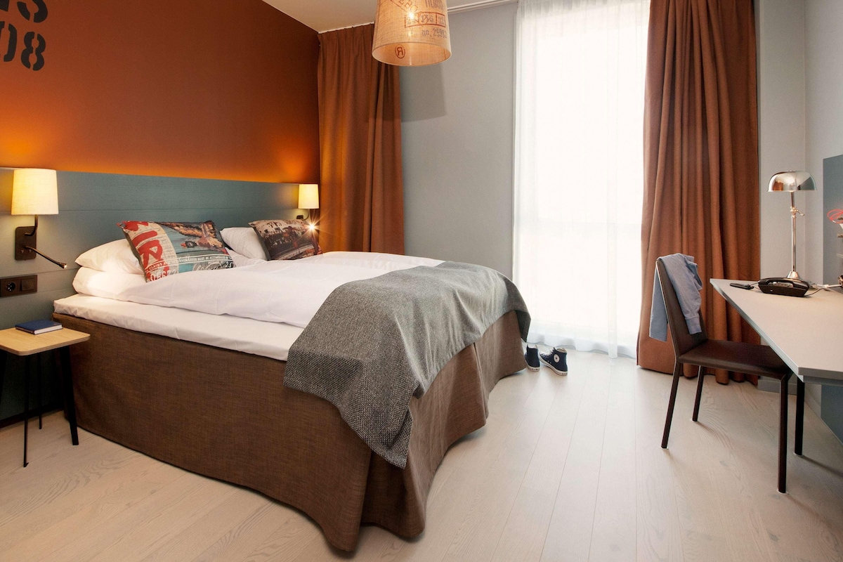 Une chambre d’hôtel moderne, dotée d’un grand lit, d’un bureau et d’une chaise.