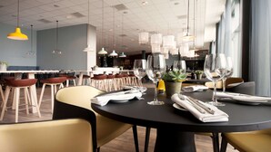 Ein modernes Restaurant mit runden Tischen, Stühlen und hängenden Pendelleuchten.