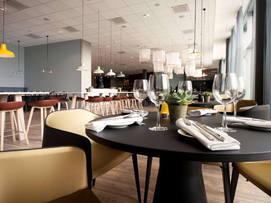 Un restaurante moderno con mesas redondas, sillas e iluminación colgante.
