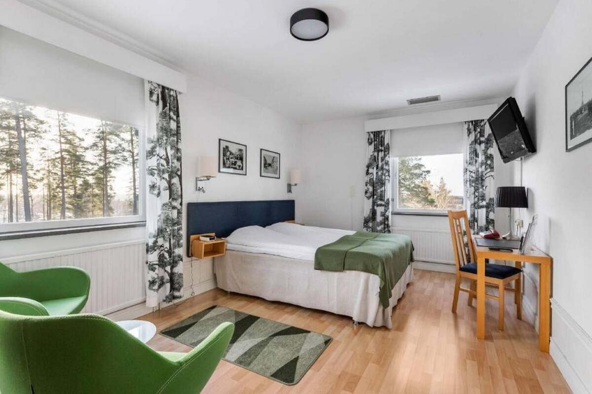 A bedroom with a bed, a desk, a chair, and a TV.