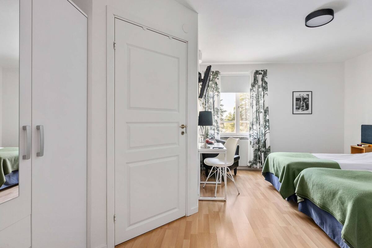 A bedroom with two beds, a desk, and a chair.