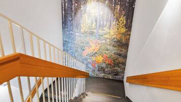 A staircase with wooden handrails leading to a wall with a forest mural.