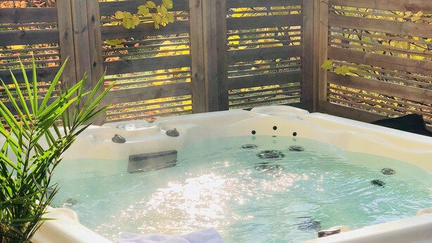 A hot tub on an outdoor deck with a wooden fence and trees in the background. - Hotel Malmkoping, BW Signature Collection (Malmkoping)