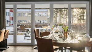 A dining area with a table set for four, large windows, and a view of buildings and trees outside. - Hotel Malmkoping, BW Signature Collection (Malmkoping)