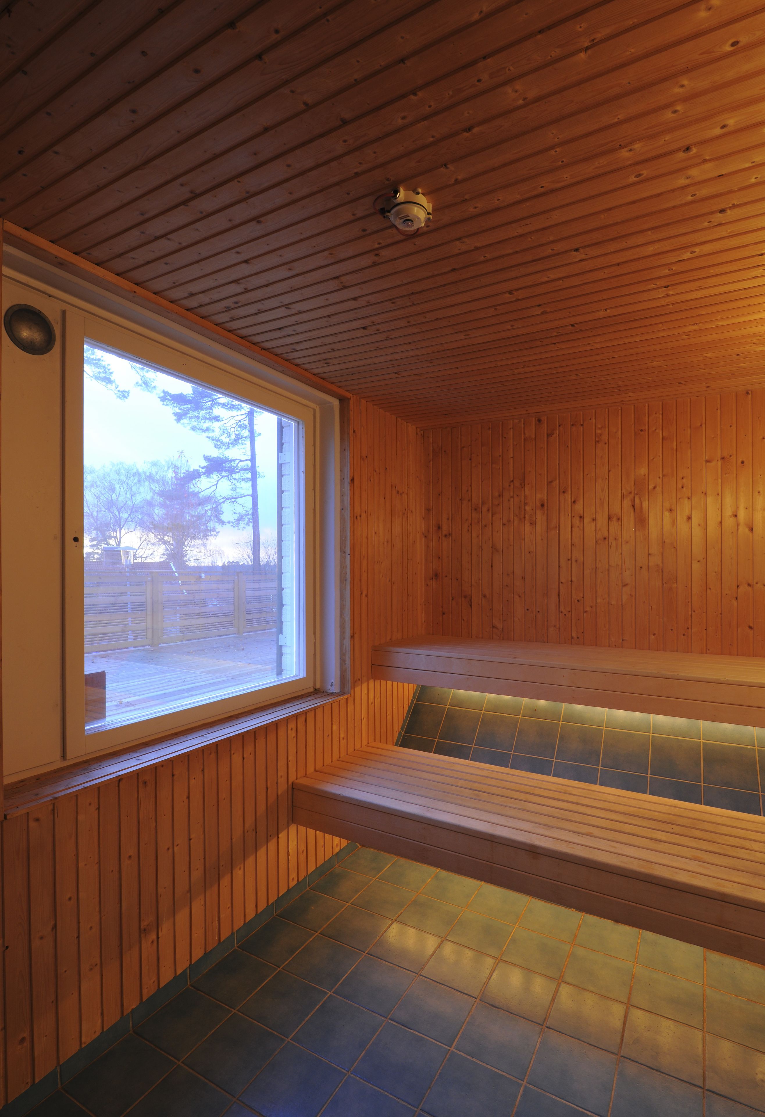 Una sauna con pareti in legno, una panchina e una finestra.