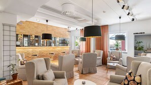 A modern lounge area with comfortable seating, a bar area, and large windows. - Hotel Malmkoping, BW Signature Collection (Malmkoping)