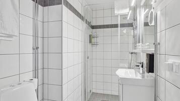 A modern bathroom with a glass-enclosed shower, a white sink, and a mirror.