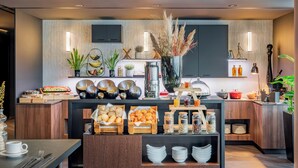 Cocina moderna con un bufé, que incluye diversas opciones de comida y una estación de café.