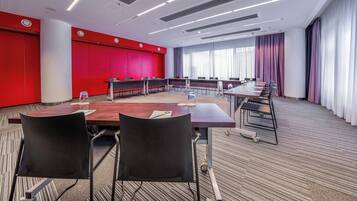 A conference room with a long table, multiple chairs, and a red accent wall.