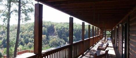 A covered outdoor area with wooden benches and a view of a forested landscape.