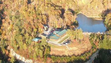 An aerial view of a lodge surrounded by dense forest and a lake.