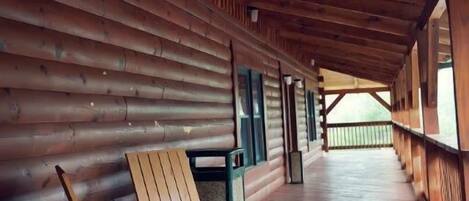 Une terrasse en bois couverte, avec une chaise en bois et une poubelle.