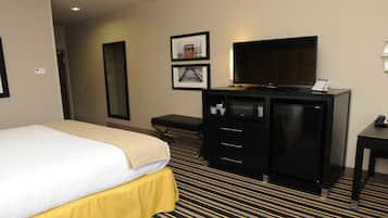 A hotel room with a bed, a desk, a television, and a minibar.