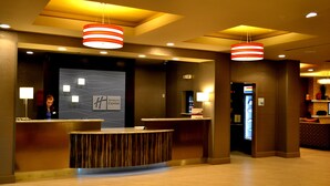 A hotel reception area with a Holiday Inn Express sign, a reception desk, and a counter. - Holiday Inn Express Covington-Madisonville by IHG (Covington)
