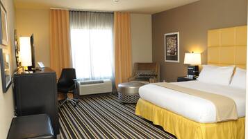 Ein Hotelzimmer mit einem Bett, einem Schreibtisch, einem Stuhl, einer Klimaanlage und einem Vorhangfenster.