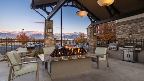 Un patio al aire libre con chimenea de piedra, mobiliario y zona de parilla.