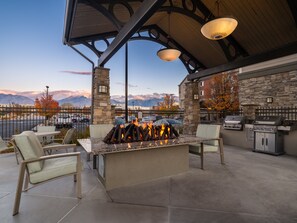 An outdoor patio with a stone fireplace, seating, and a grill area. - Staybridge Suites Midvale by IHG (Midvale)