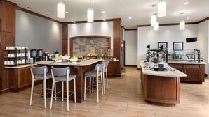 Una cocina amplia con una isla central, taburetes de bar y una pared decorativa de piedra.