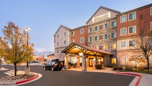 Un hotel Staybridge Suites con fachada de piedra, múltiples ventanas y una entrada cubierta.