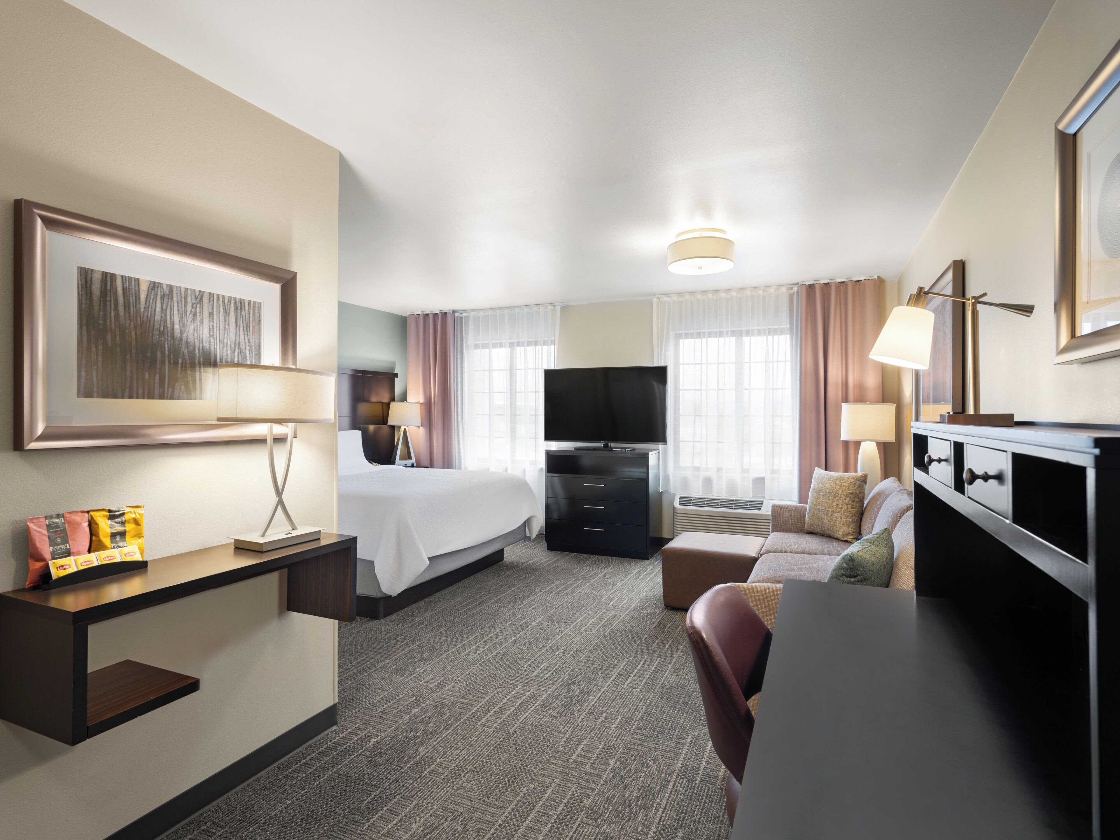 Een hotelkamer met een bed, bureau, televisie en zithoek.