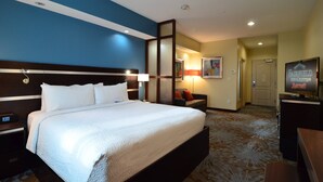 A hotel room with a large bed, a desk, a chair, a TV, and a door. - Fairfield Inn & Suites Houston-North Spring (Spring)