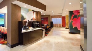 A modern hotel lobby with a reception desk, seating area, and a large floral artwork on the wall. - Fairfield Inn & Suites Houston-North Spring (Spring)