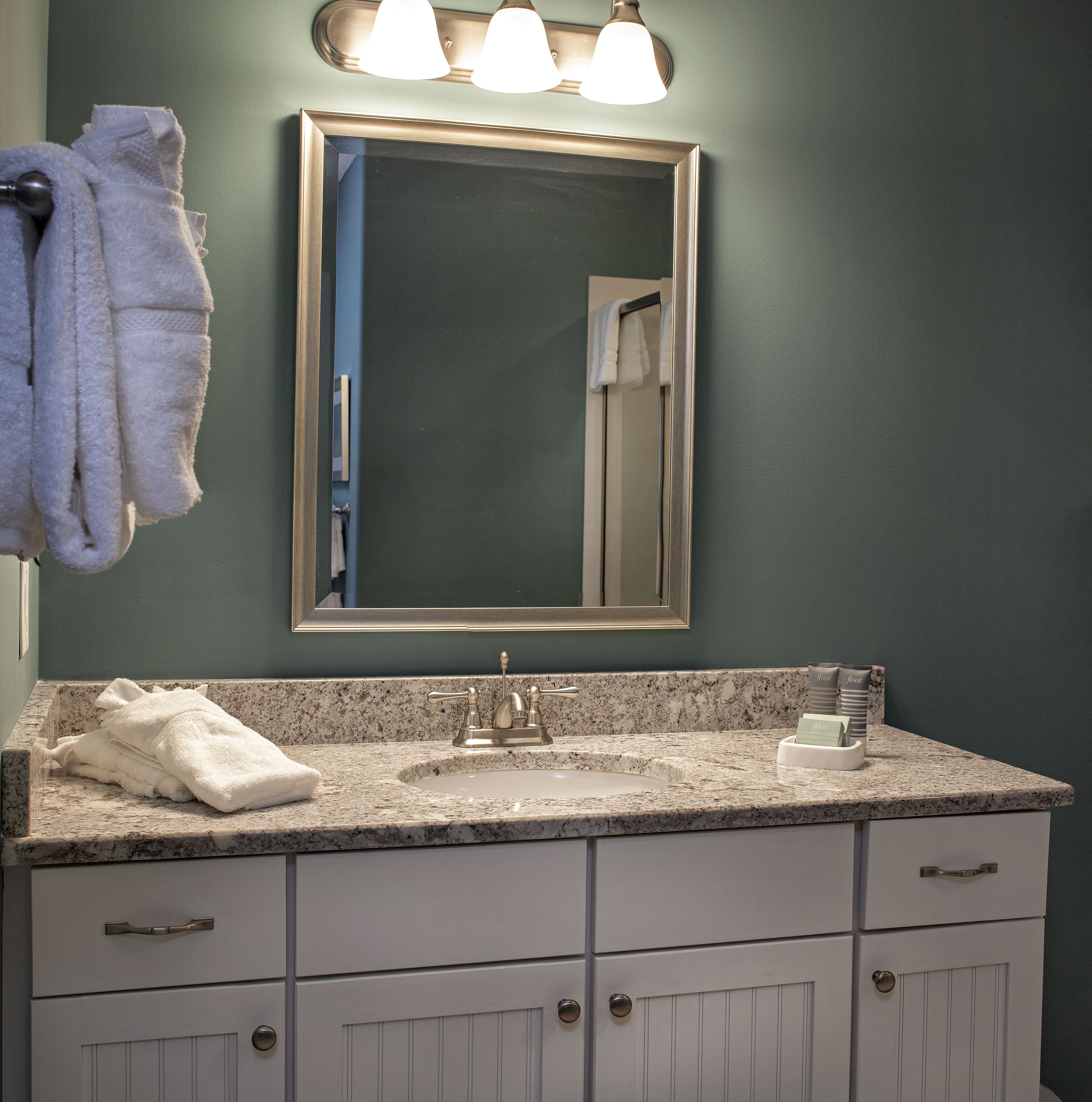 A bathroom with a sink, mirror, towel rack, and a vanity with drawers.