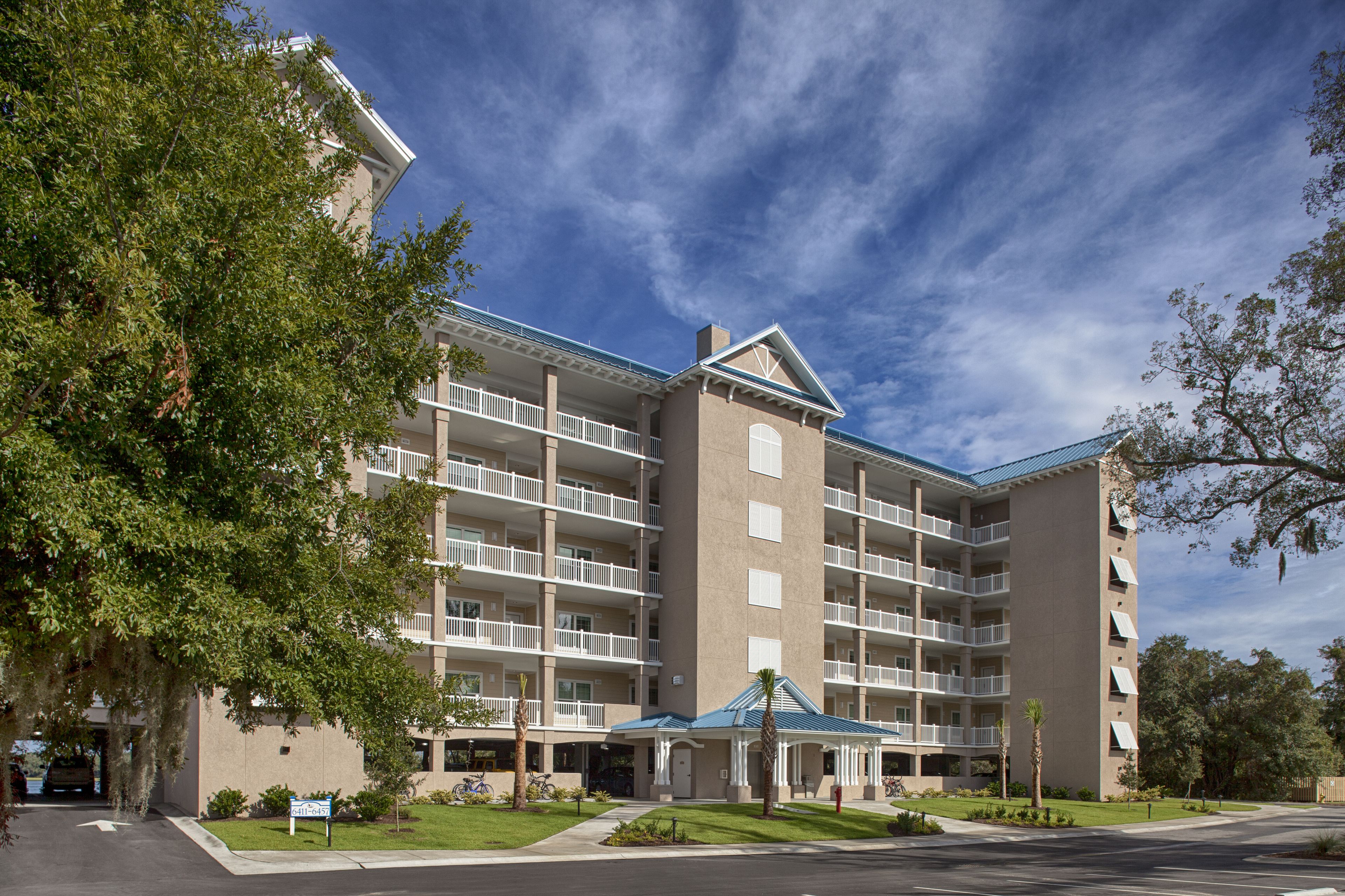 A multi-story hotel with balconies, a covered entrance, and a parking area.