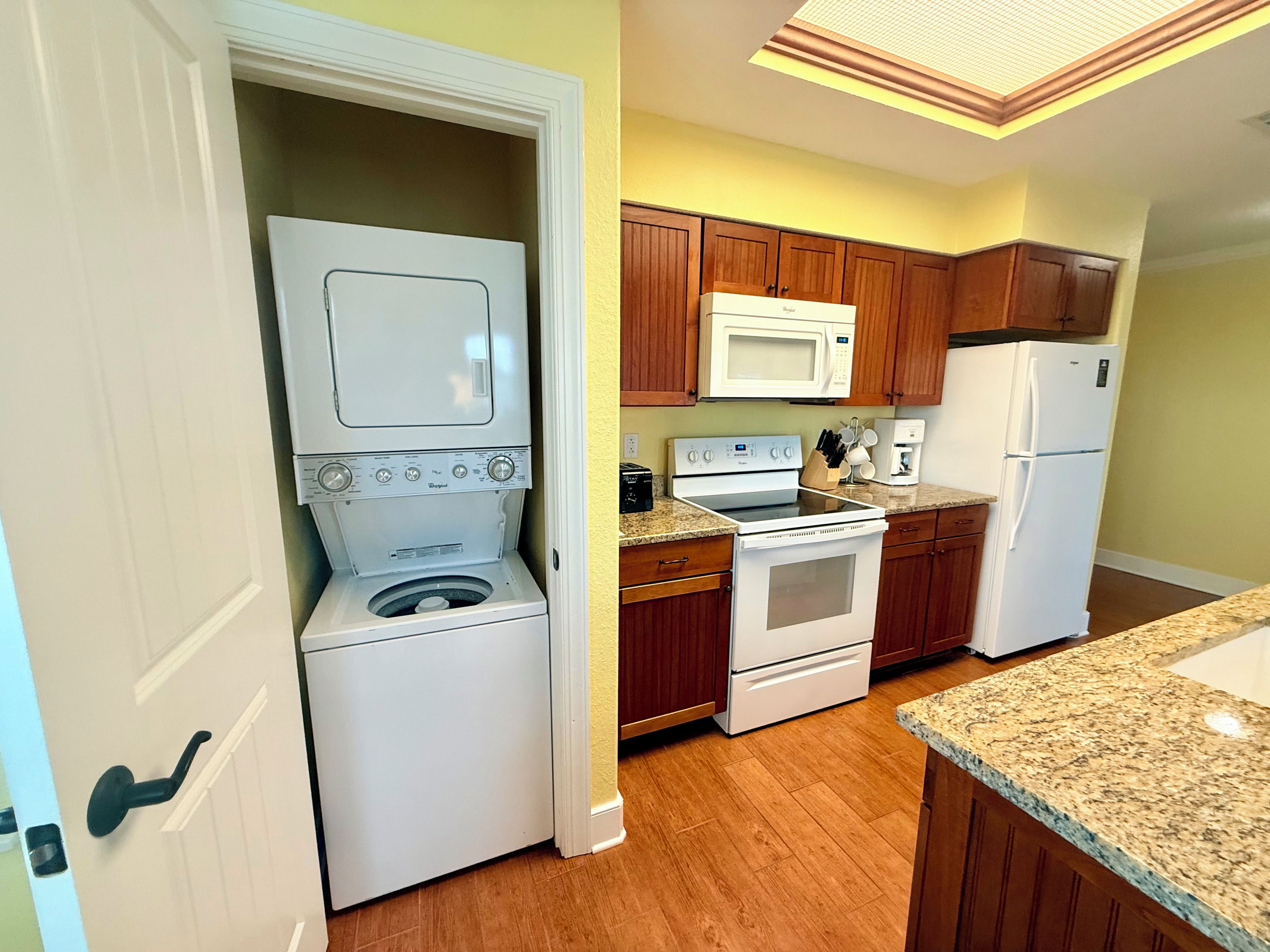 A compact kitchen with a washer-dryer unit, a microwave, an oven, and a refrigerator.