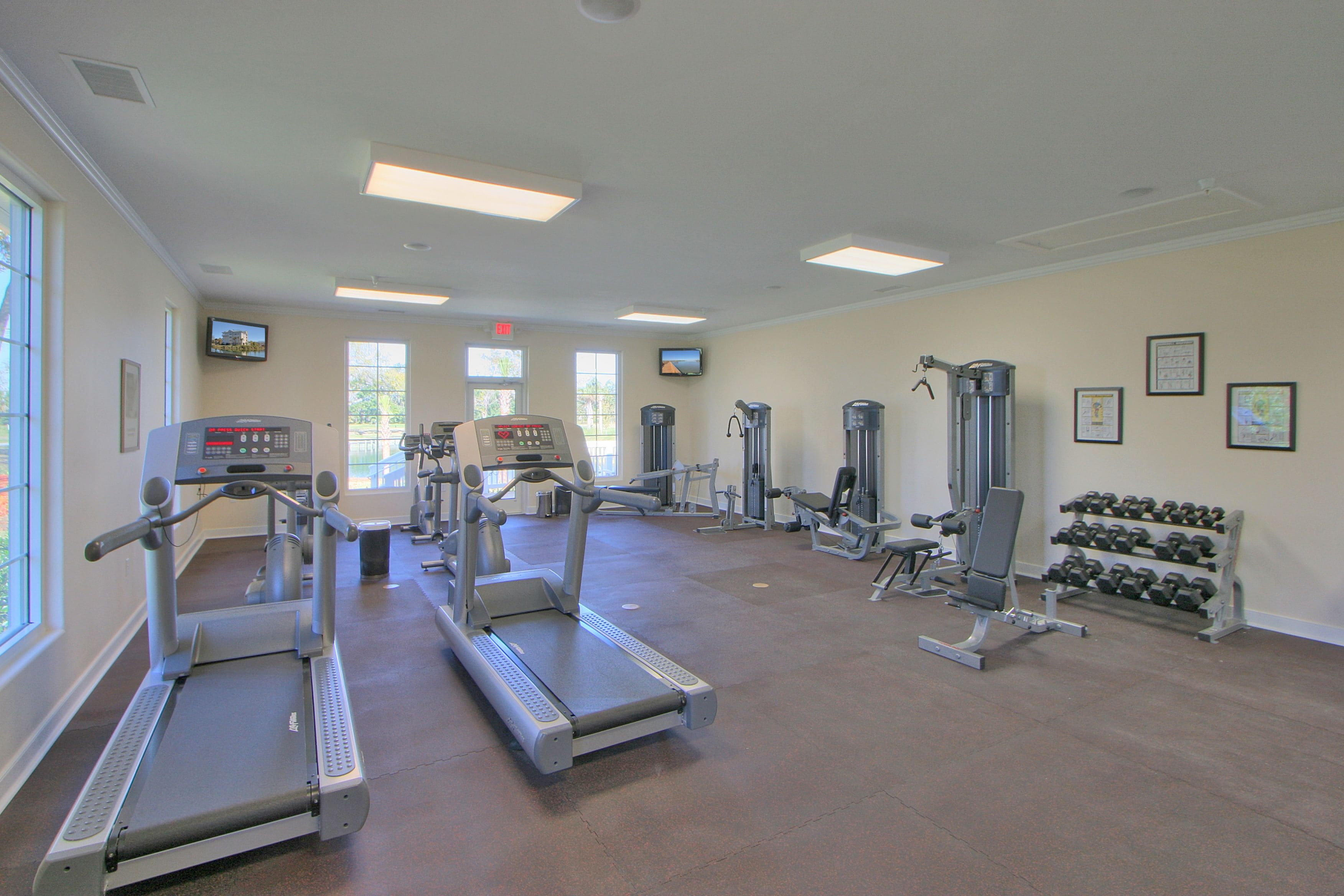 Une salle de sport équipée de tapis de course, d’appareils de musculation et d’haltères.