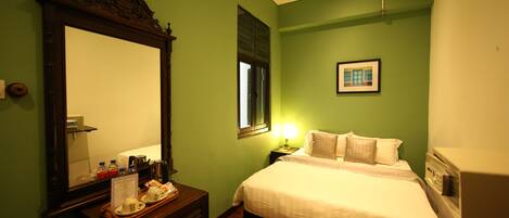 Une chambre d’hôtel avec un grand miroir, un lit avec du linge de lit blanc, une table de chevet avec une lampe et un tableau accroché au mur.