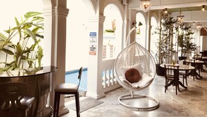 A spacious indoor area with a pool, seating arrangements, and a hanging chair. - Museum Hotel (George Town)