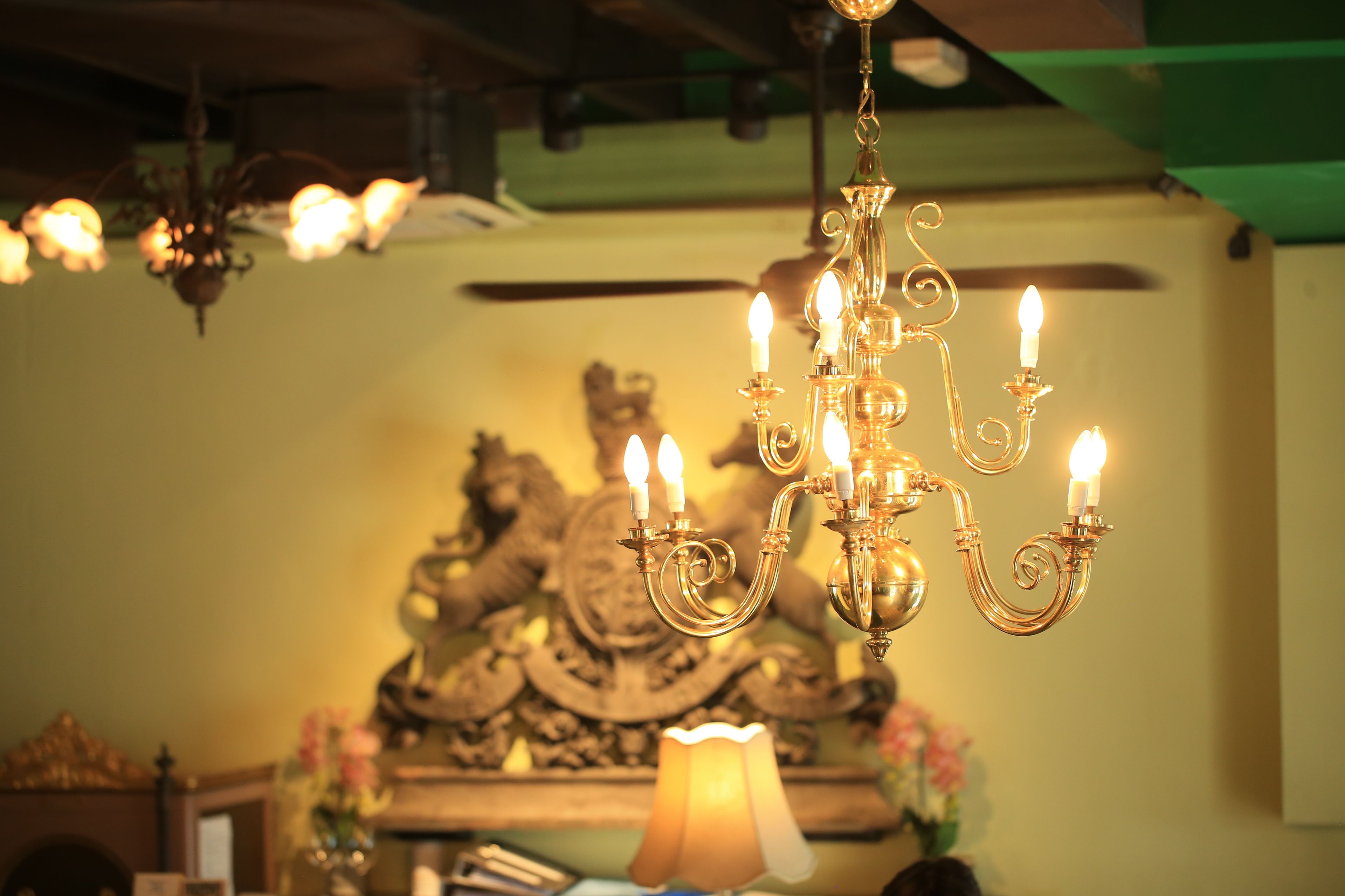 Un candelabro con múltiples luces similares a velas, un adorno de pared y una lámpara de mesa en una habitación cálidamente iluminada.