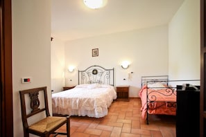 A bedroom with two beds, a chair, a nightstand, and a wall-mounted clock. - Agriturismo da Lorena (Manciano)