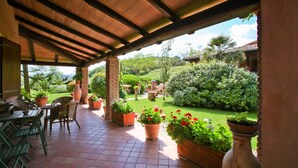 A covered patio with terracotta tiles, outdoor furniture, and potted plants. - Agriturismo da Lorena (Manciano)