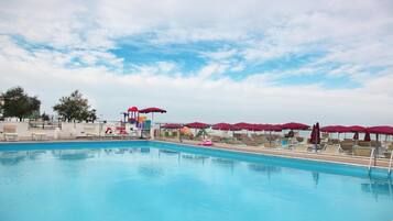 Relax by the pool surrounded by comfortable lounge chairs and shaded seating areas.
