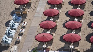 Una playa con filas de sillas de baño y sombrillas rojas, dispuestas en un patrón de cuadrícula.