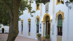 Un edificio con fachada blanca, contraventanas verdes y detalles amarillos.