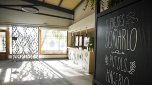 Zona de recepción con una pizarra mostrando un mensaje inspirador, un mostrador de recepción y un separador decorativo.