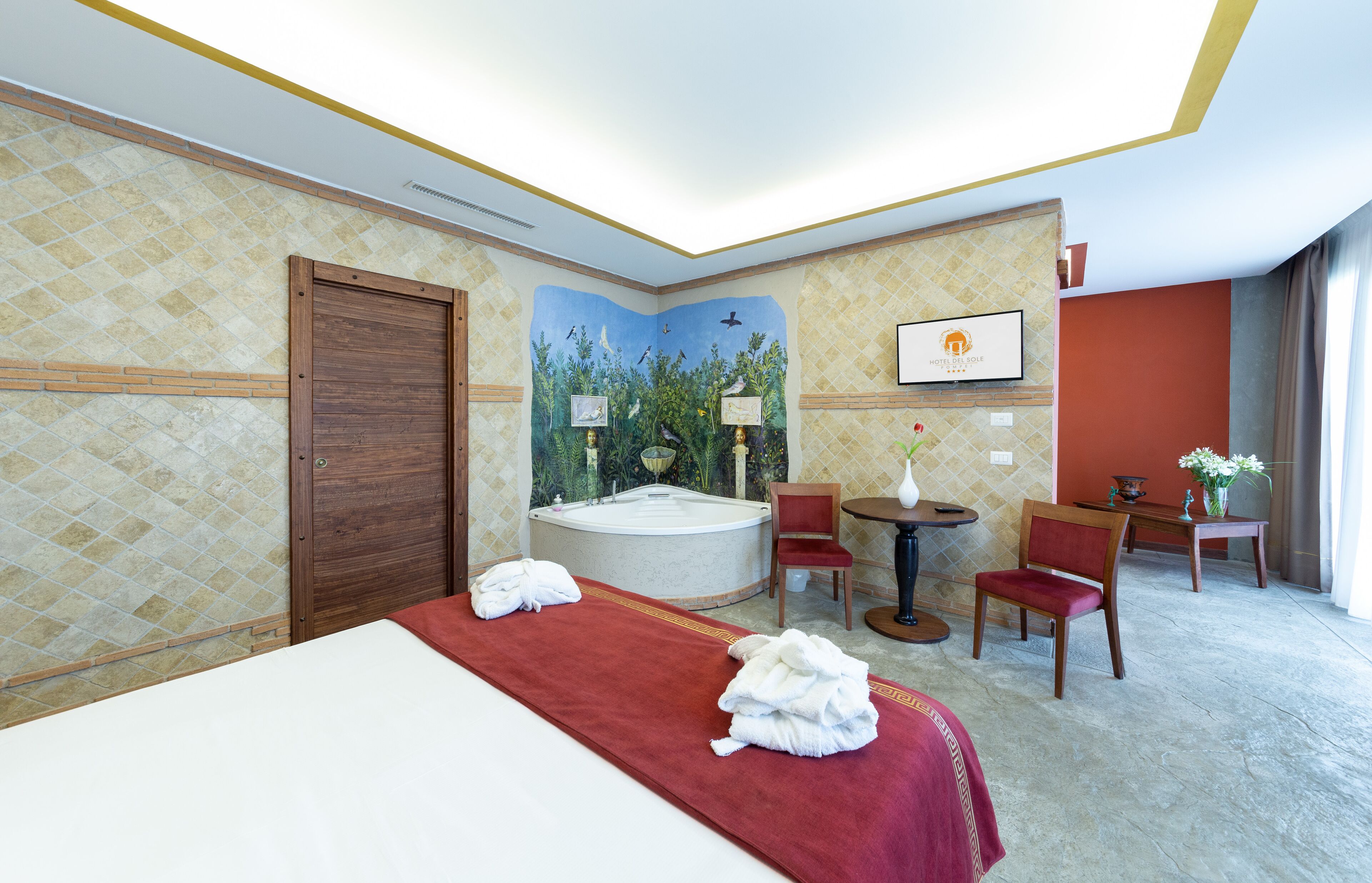 Habitación de hotel con cama, jacuzzi, escritorio y sillas.