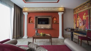 Een woonkamer met een grote televisie, een open haard, een rode muur en een muurschildering.